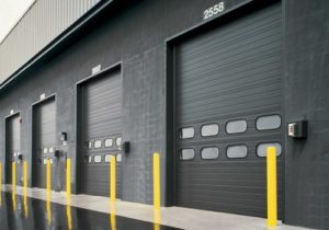 A row of rolling steel doors on the side of a large commercial building.