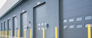 A row of commercial garage doors on a gray warehouse.